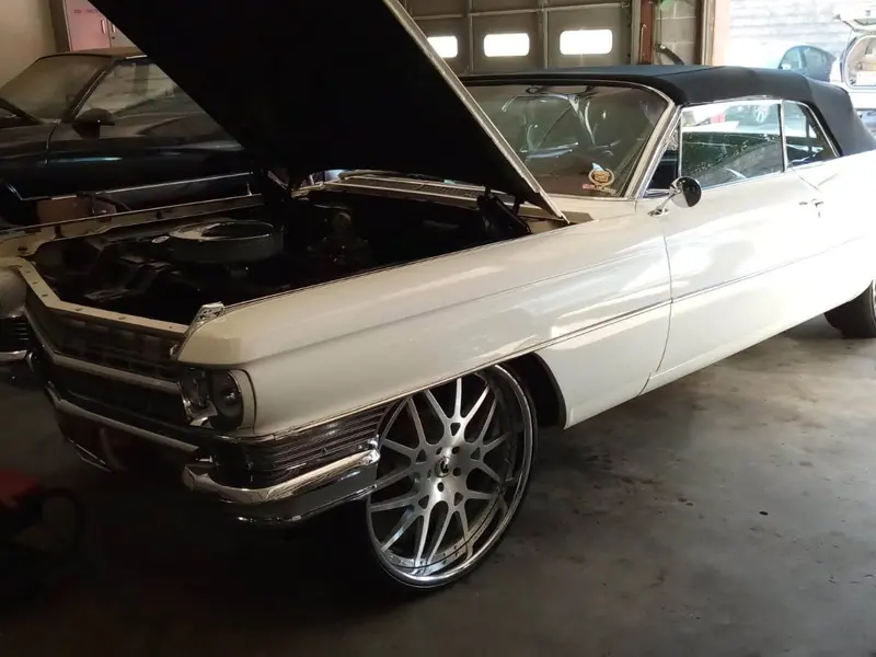 A 1964 Cadillac convertible with the hood up in the shop