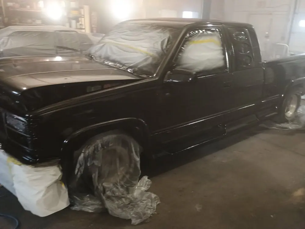 A pickup with fresh black paint on it and the glass still masked