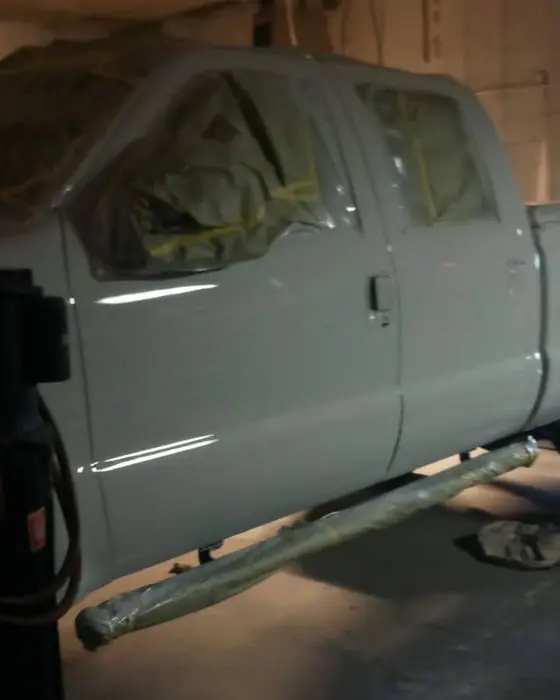 A crew-cab pickup raised on the two-post lift in the shop
