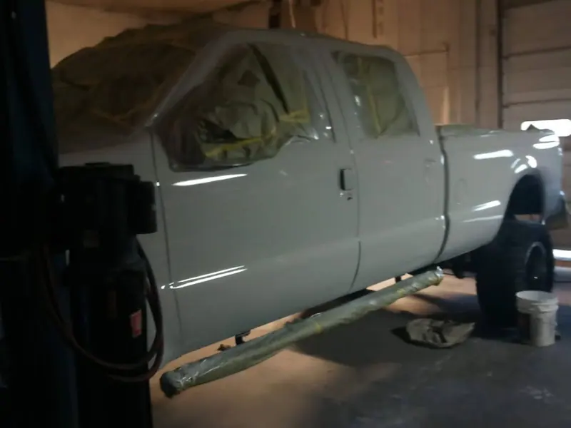 A crew-cab pickup raised on the two-post lift in the shop
