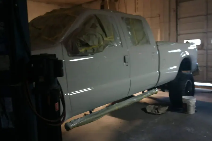 A crew-cab pickup raised on the two-post lift in the shop
