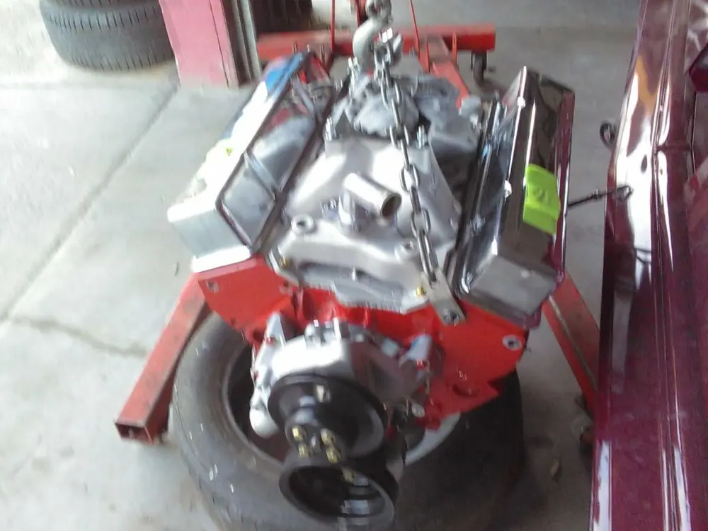 A V8 on the hoist, on its way back into the car