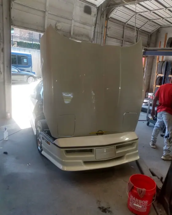A Corvette with the hood up in the bay during a body and paint job