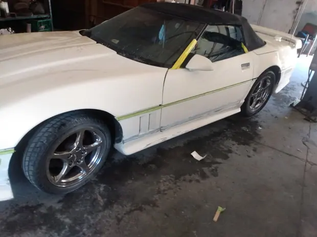 A Corvette convertible in the bay with the door and rocker being worked